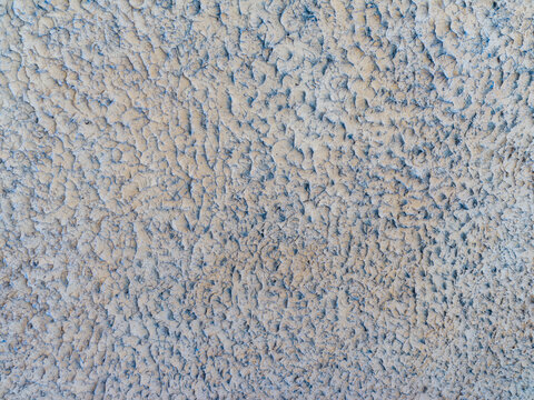 Close up macro texture of rough grey bumpy stucco wall surface outdoors