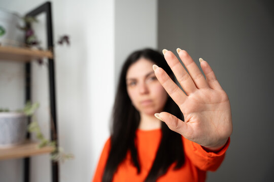 Woman in bright attire making a stop gesture with her hand indoors. Personal boundaries safety awareness and assertive communication
