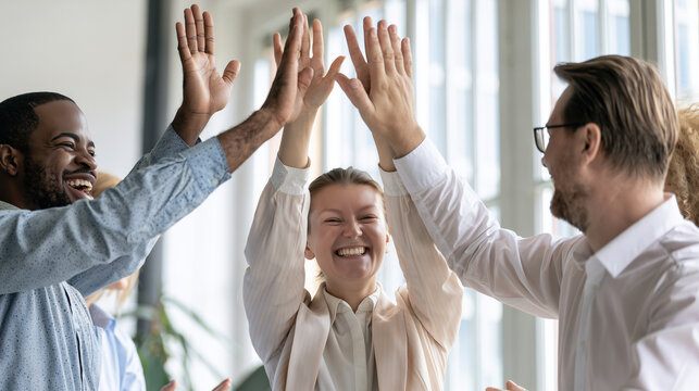 Successful Business Colleagues Celebrating Goal Achievement in Contemporary Workplace Multicultural business team smiling and celebrating a milestone with raised hands and high fiv