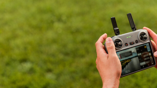 Person holding a drone remote controller with a screen displaying a landscape view