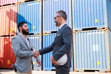 Fototapeta na wymiar Man manager and male Supervisor dock cargo checking and handshake at container yard port of import and export goods. Unity and teamwork concept