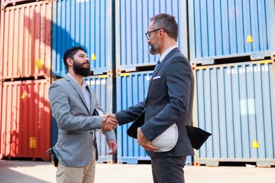 Man manager and male Supervisor dock cargo checking and handshake at container yard port of import and export goods. Unity and teamwork concept