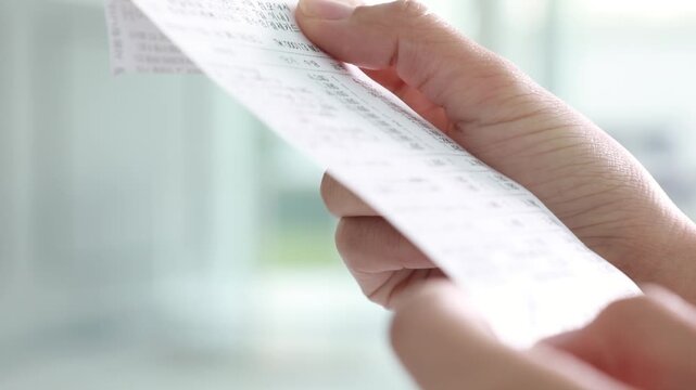 사무실에서 영수증의 상세 내역을 꼼꼼하게 확인하고 검토하는 인물의 손입니다.