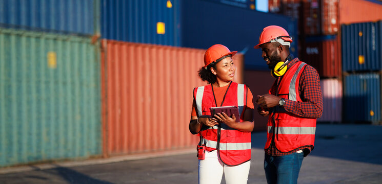 Portriat handsome male African American Industrial and female cock warehouse specialist. Black man worker wearing yellow protective hard hat helmet working at container yard.