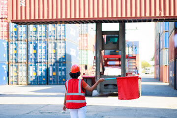 Fototapeta premium Black female dock worker control loading containers box from cargo at warehouse container yard. Marine and carrier insurance concept. cargo shipping container box in logistic shipping yard