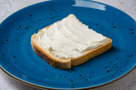 Slice of bread with cream cheese on a blue plate
