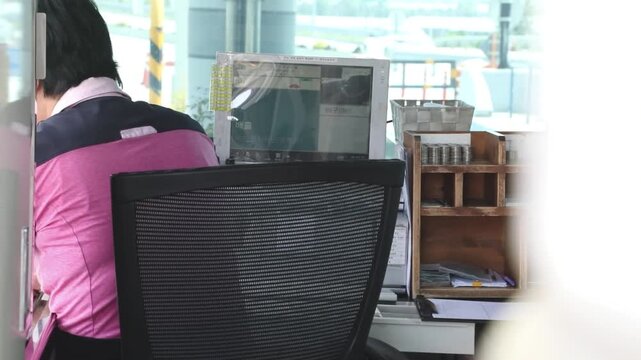 톨게이트 사무실에서 근무자가 모니터를 보며 차량 통행료 정산 업무를 수행하는 모습입니다.