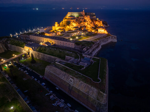 Aerial view of illuminated Old Fortress walls and moat canal at night, historic Venetian fortifications and bridge in Corfu island, UNESCO world heritage site