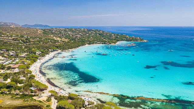 Aerial view of Plage de Santa Giulia on the southeast coast of Corsica, France, with white sand, shallow turquoise waters, Mediterranean vegetation, and a picturesque mountain backdrop