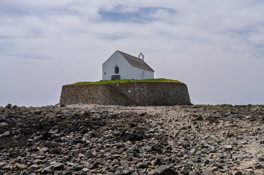 The historic medieval chapel of Eglwys Cwyfan stands on the tidal island of Cribinau off the coast of Anglesey, North Wales.