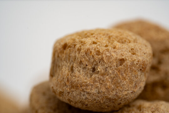 Single soya chunk in sharp focus above a pile of textured vegetable protein
