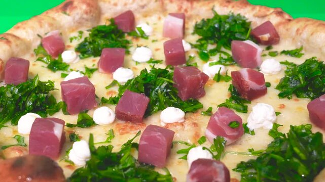 Homemade pizza photographed on a green backdrop highlighting textures and colorful toppings