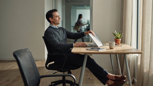 Happy Man Closing Laptop With Relieved Grin In Office