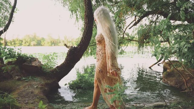 silhouette fantasy woman river nymph walking in swamp green water. happy fairy girl enjoys stroll by river bank beauty wild nature tree. Elf goddess back view wet beige golden dress. long blonde hair.
