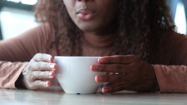 Women's hands hold a mug of hot tea in the morning during the cold season. A young woman warms her hands on a very hot cup of tea.
