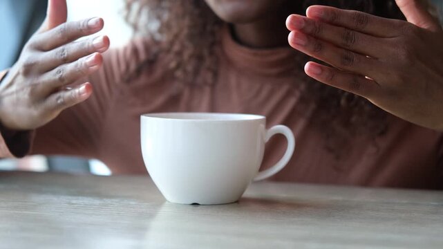 Women's hands hold a mug of hot tea in the morning during the cold season. A young woman warms her hands on a very hot cup of tea.