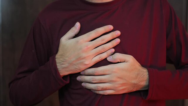 A young man in a light shirt experiences pain in the heart due to severe stress. Heart attack and panic attack. Health problems of the guy