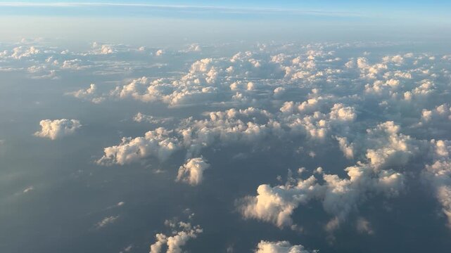 View from Airplane Window Above Beautiful Clouds. Sunset Warm Light. United States Utah. Plane Flight Aerial Wide.