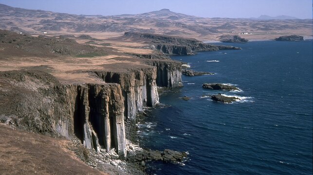 Dramatic rugged coastal cliffs meeting the deep blue ocean under a clear sky