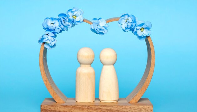 Two Wooden Peg Dolls Standing Under a Heart Shaped Wooden Arch Decorated with Blue Flowers Over a Bright Blue Background