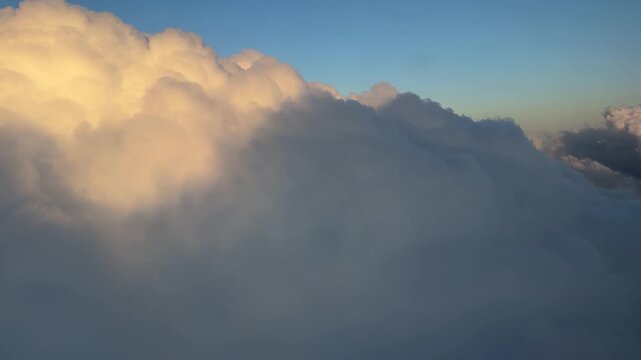 Flying Through Clouds at Sunset View From Airplane Window. Fluffy Clouds Blue Sky Shadow of Plane Appears. Aerial Flight Above the United States