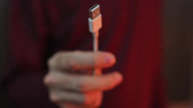 Close Up of Hand Holding Micro USB Charging Cable Connector with Blurred Background