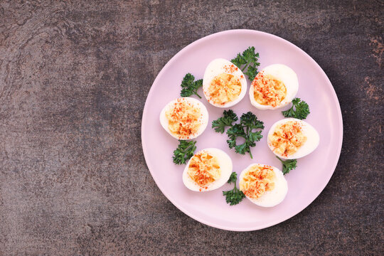 Traditional deviled eggs. Overhead view on a dark stone background.
