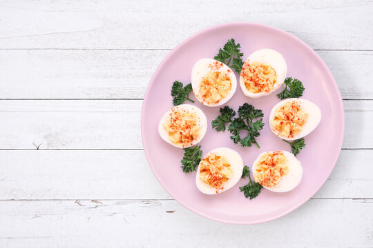 Classic deviled eggs. Top down view on a white wood table background.