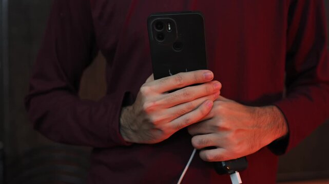 Close Up of Hand Holding Smartphone While Charging with USB Cable