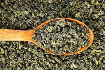 Green oolong tea scoop on flat background wooden spoon macro © Alexander