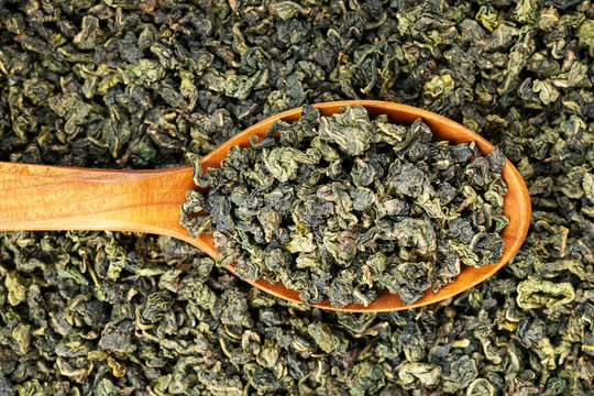 Green oolong tea scoop on flat background wooden spoon macro