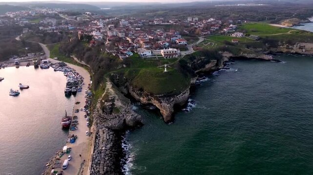 Aerial drone view of a coastal village with harbor and lighthouse, 4k video footage