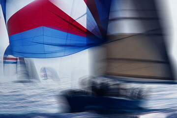 Fototapeta premium Vintage 35mm film scan of sailboat regatta, colorful spinnaker and racing yachts on sparkling sea, intentional motion blur, abstract sport background.