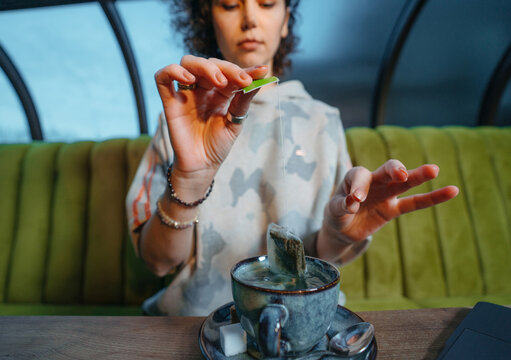 Woman brewing a fresh mug of tea with teabag in cafe