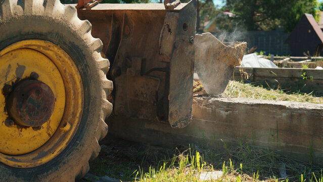 Demolition machinery breaking apart a concrete foundation wall with an impact hammer attachment, creating dust and debris at a construction site