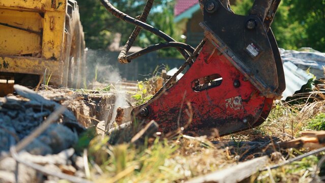 Hydraulic breaker demolishing an old concrete foundation with dust and rubble during residential site redevelopment and foundation removal.