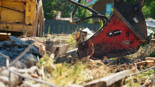 Heavy demolition machinery using a powerful hydraulic hammer attachment to break apart concrete and structural elements during urban renovation or building project