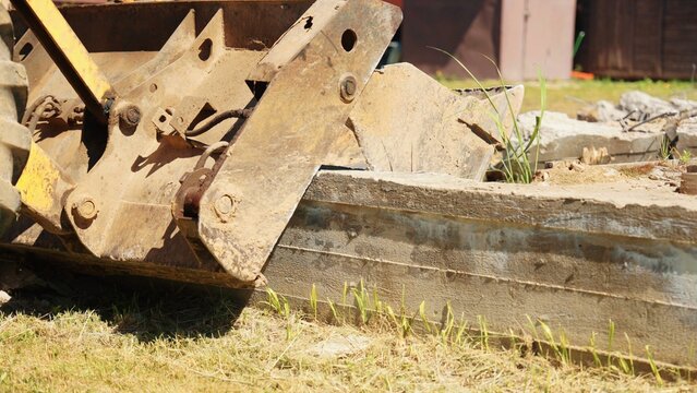 Bulldozer bucket crushing and breaking pieces of concrete slab during a demolition and construction project on a sunny day