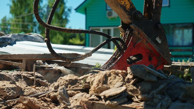 Hydraulic breaker on an excavator performing heavy demolition work, crushing concrete and rubble, creating dust at a construction site for new development