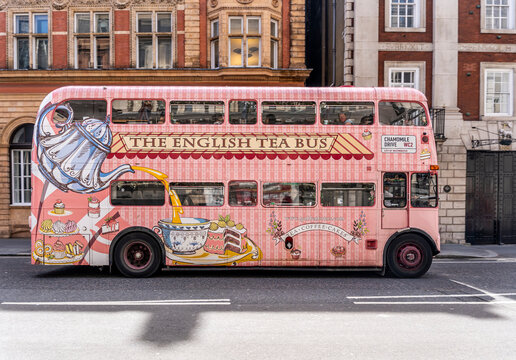 The English Tea Bus, a vintage pink double-decker bus offering traditional Afternoon Tea while touring London's streets. A popular tourist attraction along the Strand, City of Westminster, London, UK.