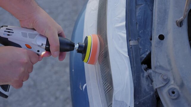The process of polishing car headlights outdoors. 