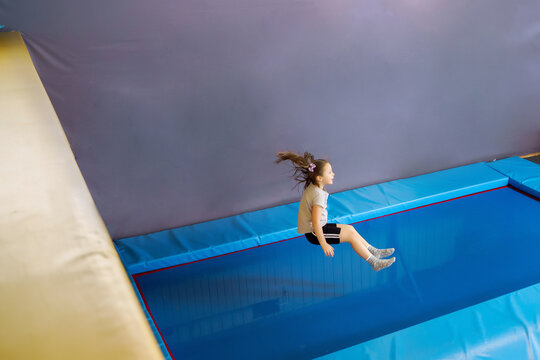 Happy little girl jumping on trampoline in fitness center