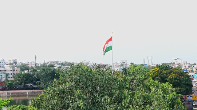 Video of the Indian national flag waving on a tall flagpole above a city