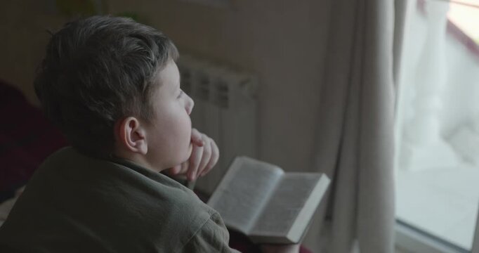 Caucasian Boy Kid Read Bible Book Lying on Bed in Bedroom. 4K 10-bit