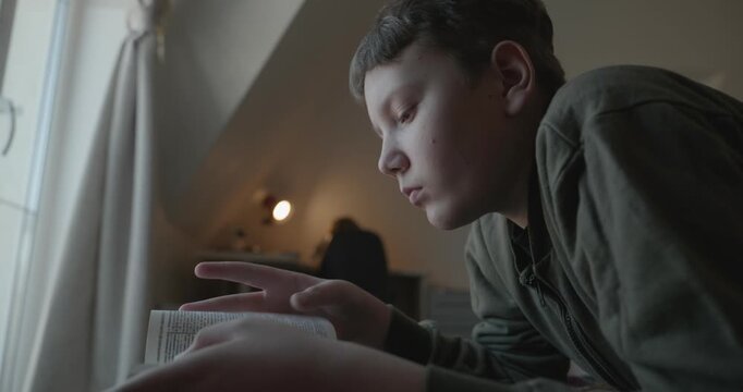 Caucasian Boy Kid Read Bible Book Lying on Bed in Bedroom. 4K 10-bit