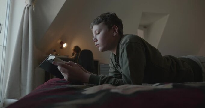 Caucasian Boy Kid Read Bible Book Lying on Bed in Bedroom. 4K 10-bit