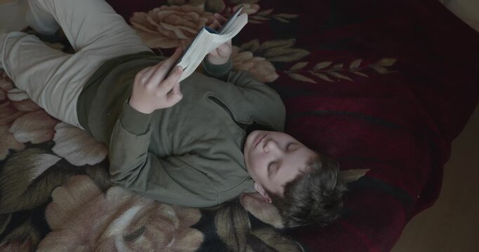 Caucasian Boy Kid Read Bible Book Lying on Bed in Bedroom. 4K 10-bit