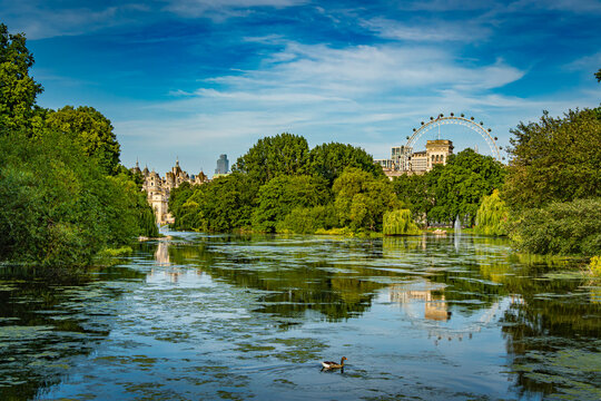 View of St James Park in London England with water, greenery, and the London Eye in the distance during daytime in a city