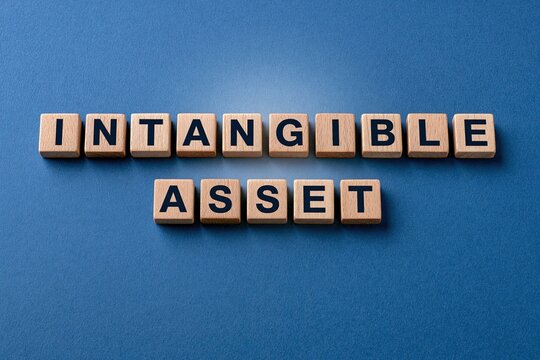Conceptual intangible asset written with wooden letter tiles on a blue background