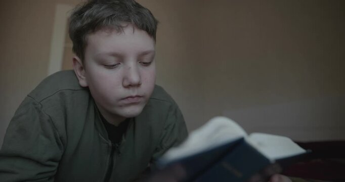 Caucasian Boy Kid Read Bible Book Lying on Bed in Bedroom. 4K 10-bit